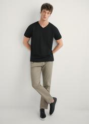 Ciemnobeżowe spodnie męskie SPOMT-0121-1K(W26)- widok produktu z przodu, na modelu, na jasnym tle. Widoczna cała sylwetka.