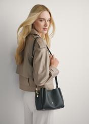 Czarna torebka damska na ramię TOREC-1182-99(W26) - widok produktu lekko po skosie na modelce, na jasnym tle. Widoczna połowa sylwetki.