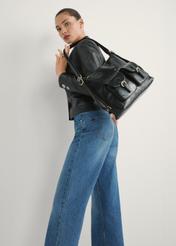 Czarny damski plecak typu worek TOREC-1193-99(W26) - widok produktu lekko po skosie, na jasnym tle. Widoczna sylwetka do kolan.