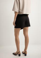 Czarne spódnico-spodenki damskie SZODT-0008-99(W26), widok produktu z tyłu na modelce. Widoczna połowa sylwetki.