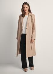 Beżowy skórzany płaszcz damski KURDS-0613-1B(W26) - widok produktu na modelce z przodu, na jasnym tle. Widoczna cała sylwetka. 