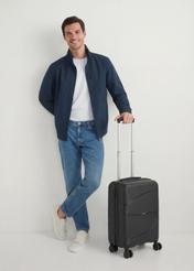 Walizka mała na kółkach WALPP-0021-99-19(W25), widok produktu skosem przy modelu, widoczna cała modelka.