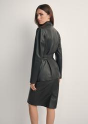 Czarna skórzana marynarka damska z paskiem KURDS-0545-99(W26), widok produktu z tyłu na modelce. Widoczna połowa sylwetki.