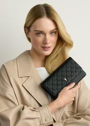 Mała torebka damska w kolorze czarnym TOREC-1178-9P(W26), widok produktu w dłoni modelki, na jasnym tle.