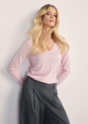 Jasnoróżowy sweter damski SWEDT-0250-34(Z25), widok produktu z przodu na modelce. Widoczna połowa sylwetki.