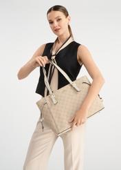 Beżowa torebka shopper z monogramem TOREC-1029-81(W25) - widok na modelce na białym tle. Widoczna połowa sylwetki. 