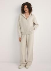 Beżowe szerokie spodnie damskie SPODT-0121-1A(W26), widok produktu z przodu na modelce. Widoczna cała sylwetka.