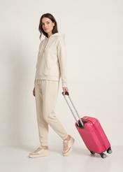 Walizka mała na kółkach WALAB-0040-5E-19(W26), widok produktu skosem przy modelce, widoczna cała sylwetka.