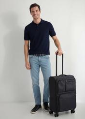 Walizka średnia na kółkach WALNY-0048-99-24(W26), widok produktu skosem obok sylwetki modela.