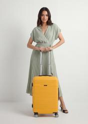 Walizka średnia na kółkach WALAB-0040-2B-24(W26), widok produktu od przodu przy modelce, widoczna cała sylwetka.