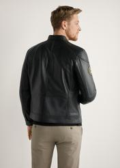 Skórzana czarna kurtka męska KURMS-0301A-99(W26) - widok produktu z tyłu, na modelu, na jasnym tle. Widoczna połowa sylwetki. 