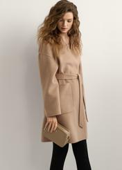 Beżowa mała torebka damska TOREC-1126-1D(W26), widok produktu w dłoni modelki. Widoczna połowa sylwetki.