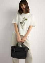 Czarna torebka typu lunchbox TOREN-0346-99(W26) - widok produktu trzymanego przez modelkę w ręku, na jasnym tle. Widoczna sylwetka do kolan.