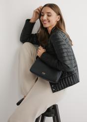 Czarna skórzana torebka damska TORES-1277-9I(W26) - widok produktu z przodu, na modelce, na jasnym tle. Widoczna sylwetka do połowy. 