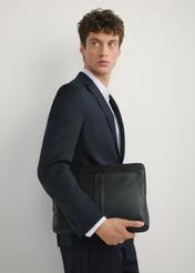 Czarna skórzana teczka na laptop TORMS-0455-99(W25), widok produktu od przodu na modelu, widoczna połowa sylwetki.