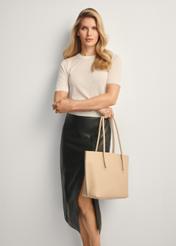 Beżowa torebka shopper damska TOREC-0938-1A(W26), widok produktu przodem na modelce, widoczna połowa sylwetki.