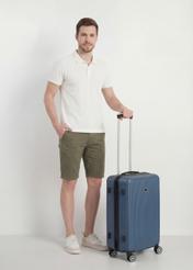 Walizka średnia na kółkach WALAB-0053-7D-24(W26), widok produktu skosem przy modelu, widoczna cała sylwetka.