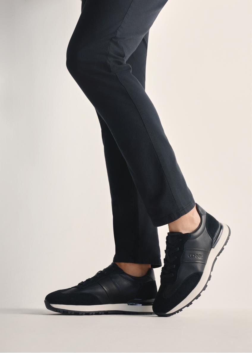 Czarne sportowe buty męskie BUTYM-0510-99(Z25), widok produktu na stopach modela na jasnym tle.