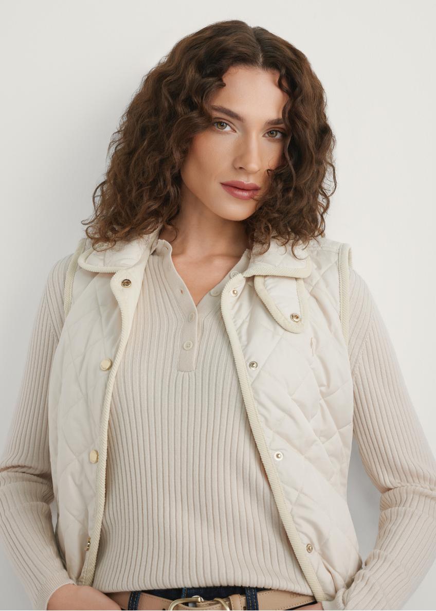 Jasnobeżowa pikowana kamizelka damska KAMDT-0036-0B(W26) - widok produktu z przodu, na modelce, na jasnym tle. Widoczna połowa sylwetki. 