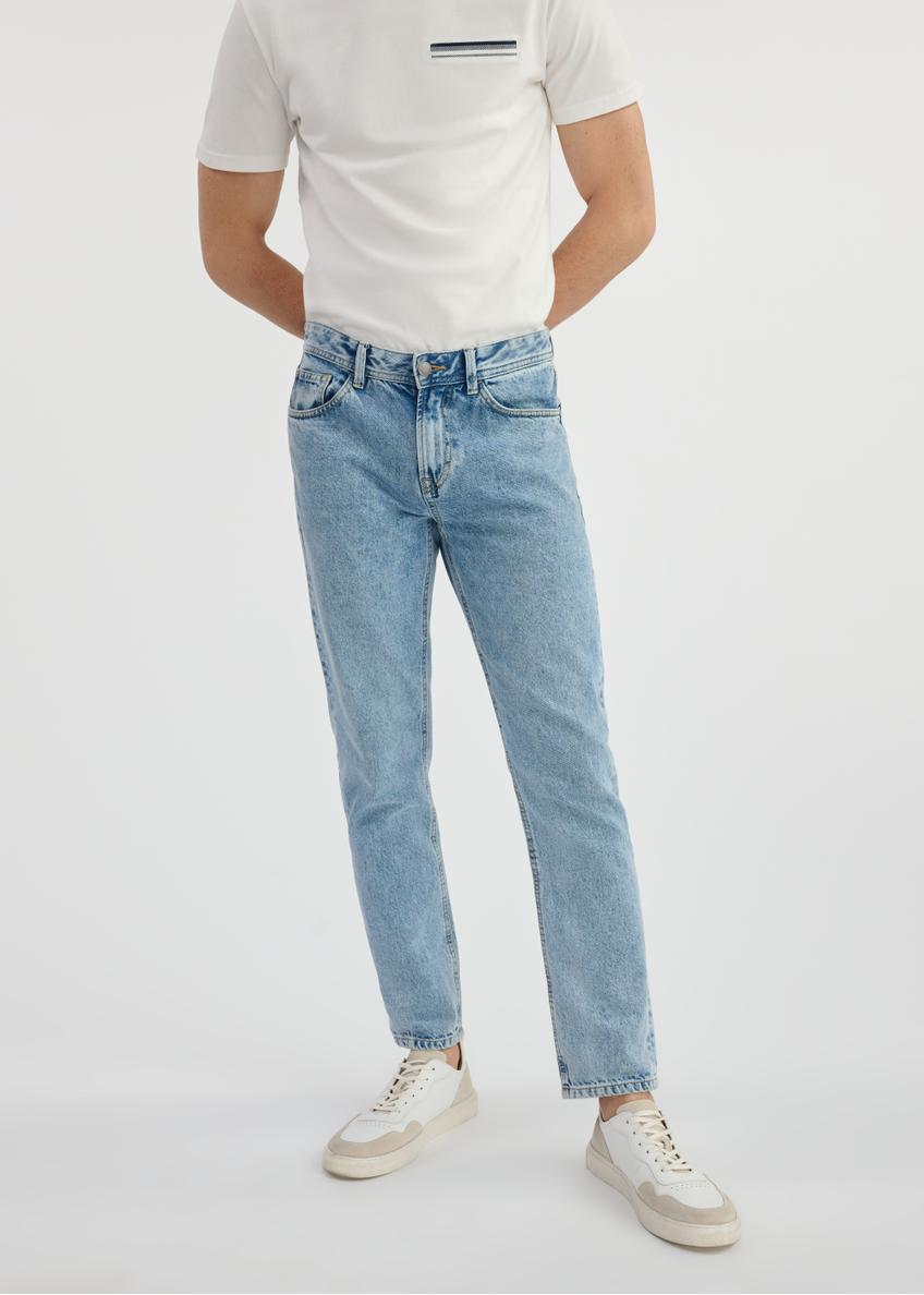 Niebieskie spodnie jeansowe męskie JEAMT-0024-60(W25) - widok produktu z przodu na modelu na białym tle. Widoczna połowa sylwetki. 