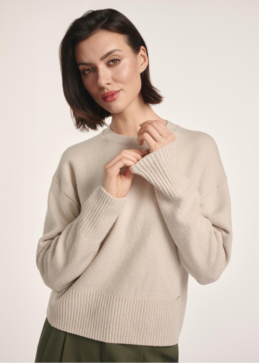 Beżowy sweter damski SWEDT-0242-80(Z25), widok produktu z przodu na modelce. Widoczna połowa sylwetki.