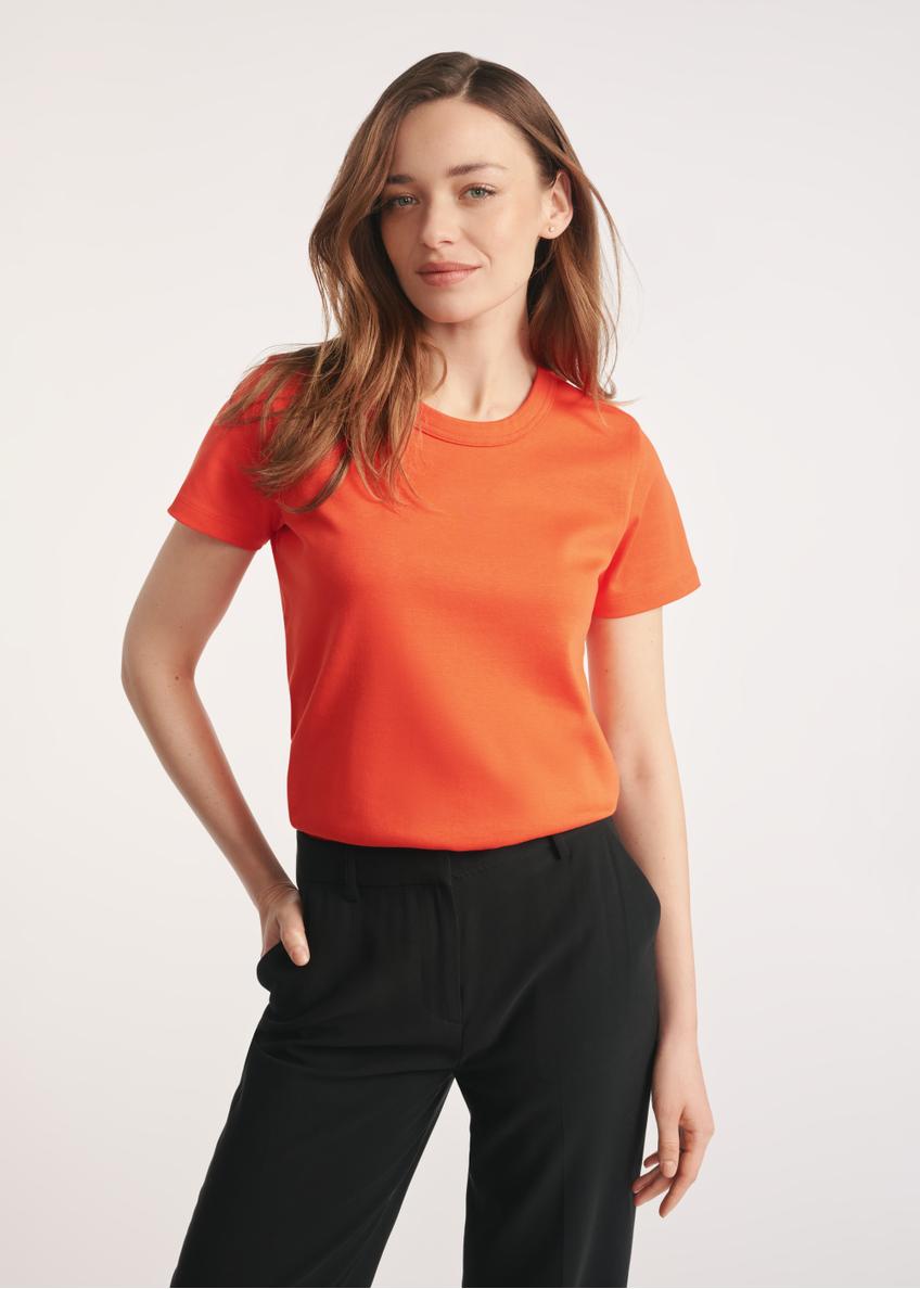 Pomarańczowy bawełniany T-shirt damski TSHDT-0144-30(Z25) - widok produktu z przodu na modelce na białym tle. Widoczna połowa sylwetki. 