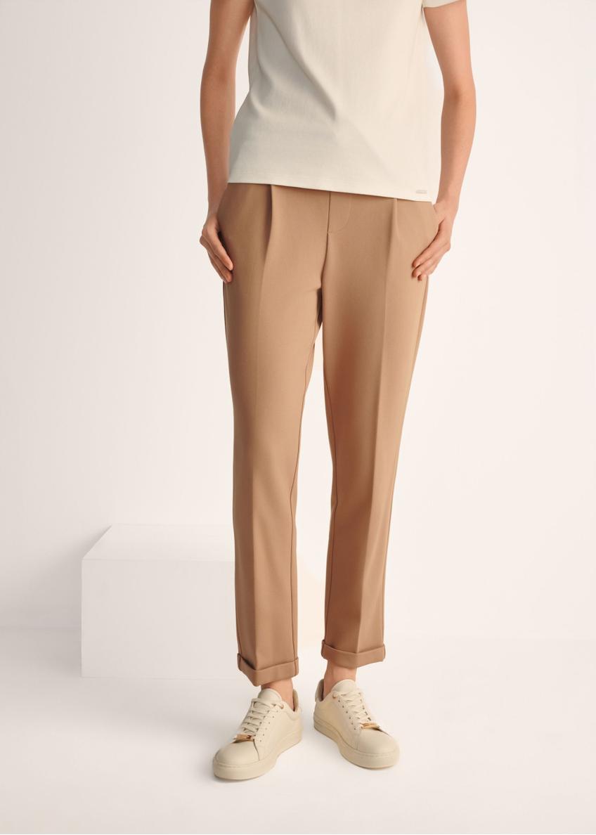 Białe skórzane tenisówki damskie BUTYD-1068-0B(W26), widok produktu na stopach modelki na jasnym tle.