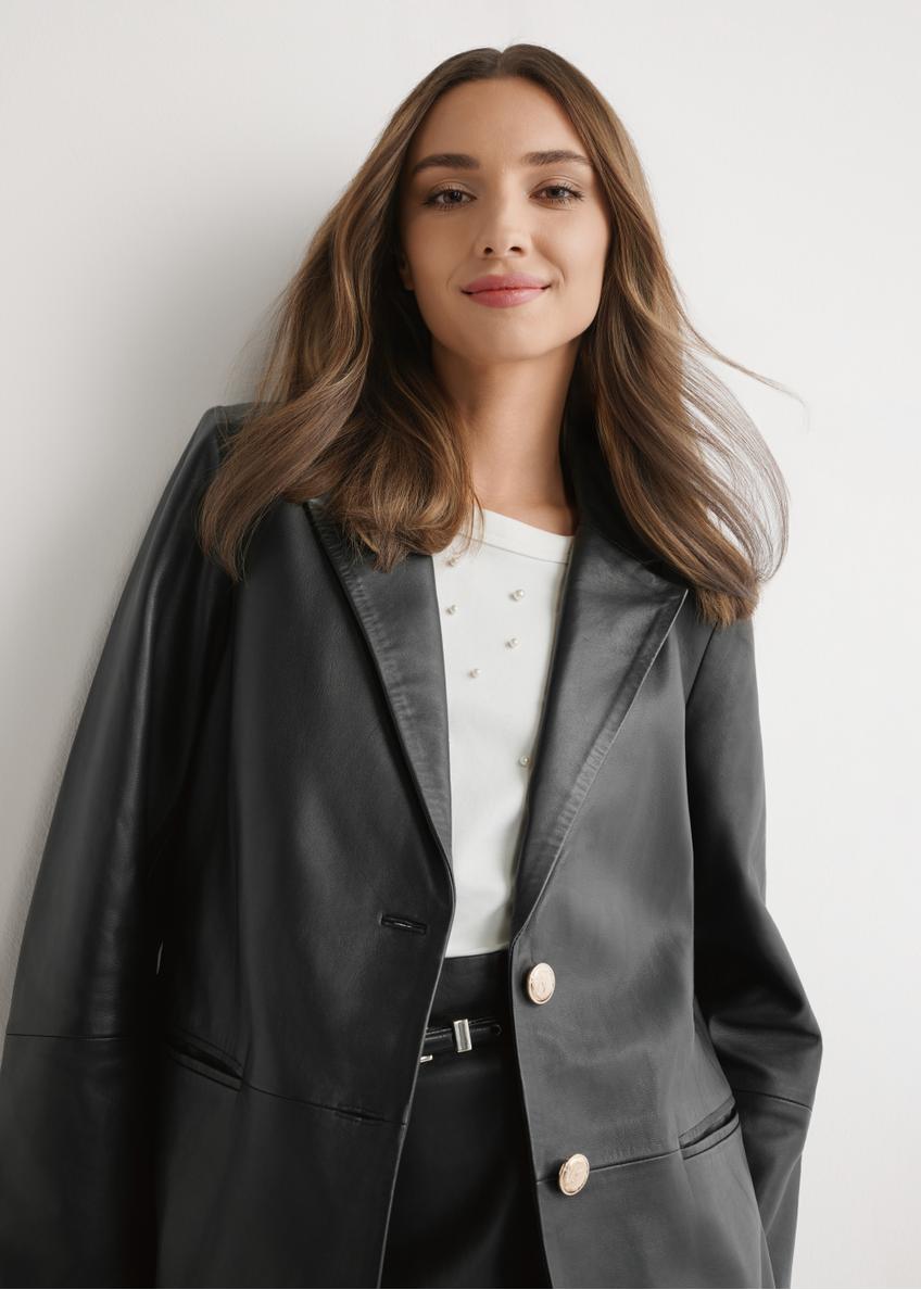 Czarna skórzana marynarka damska KURDS-0606-99(W26) - widok produktu z przodu, na modelu, na jasnym tle. Widoczna połowa sylwetki. 