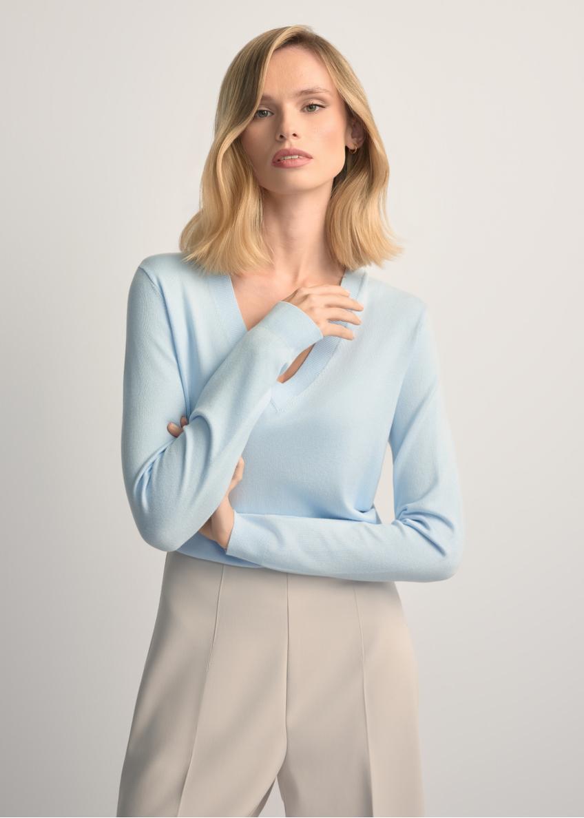 Jasnoniebieski sweter z dekoltem V-neck SWEDT-0201-7A(W26) - widok produktu z przodu, na modelce, na jasnym tle. Widoczna połowa sylwetki.