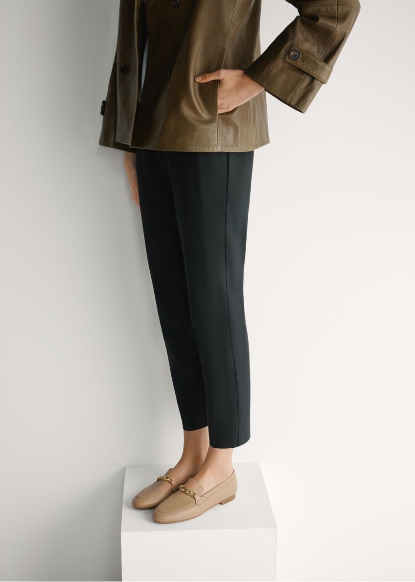 Skórzane ciemnobeżowe mokasyny damskie z łańcuszkiem BUTYD-0914A-1B(W26), widok produktu skosem na stopach modelki.